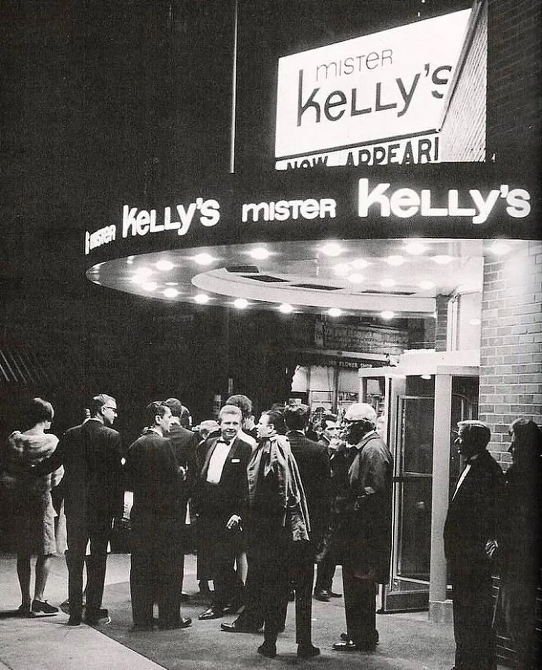 Black and white photo of a crowd in formal attire gathered outside Mister Kelly's club, under a lighted marquee.