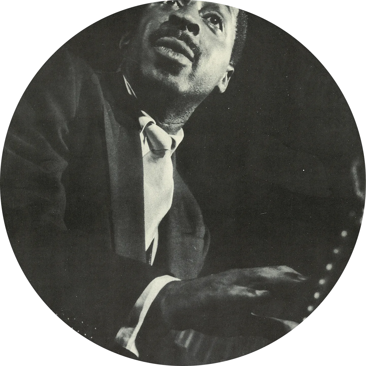 Black and white close-up of Erroll Garner playing piano, looking upward thoughtfully.
