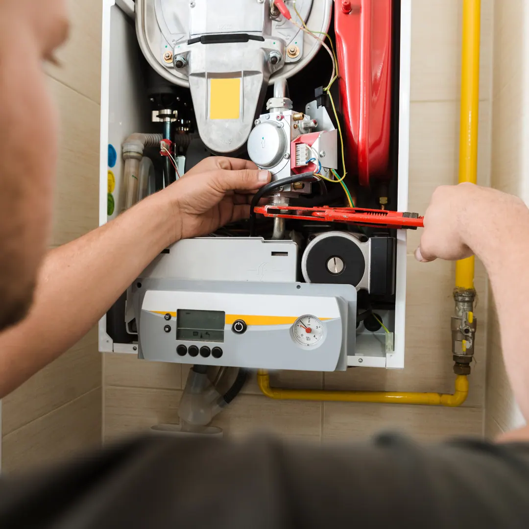 Technician using a red wrench on gas piping of a wall-mounted furnace