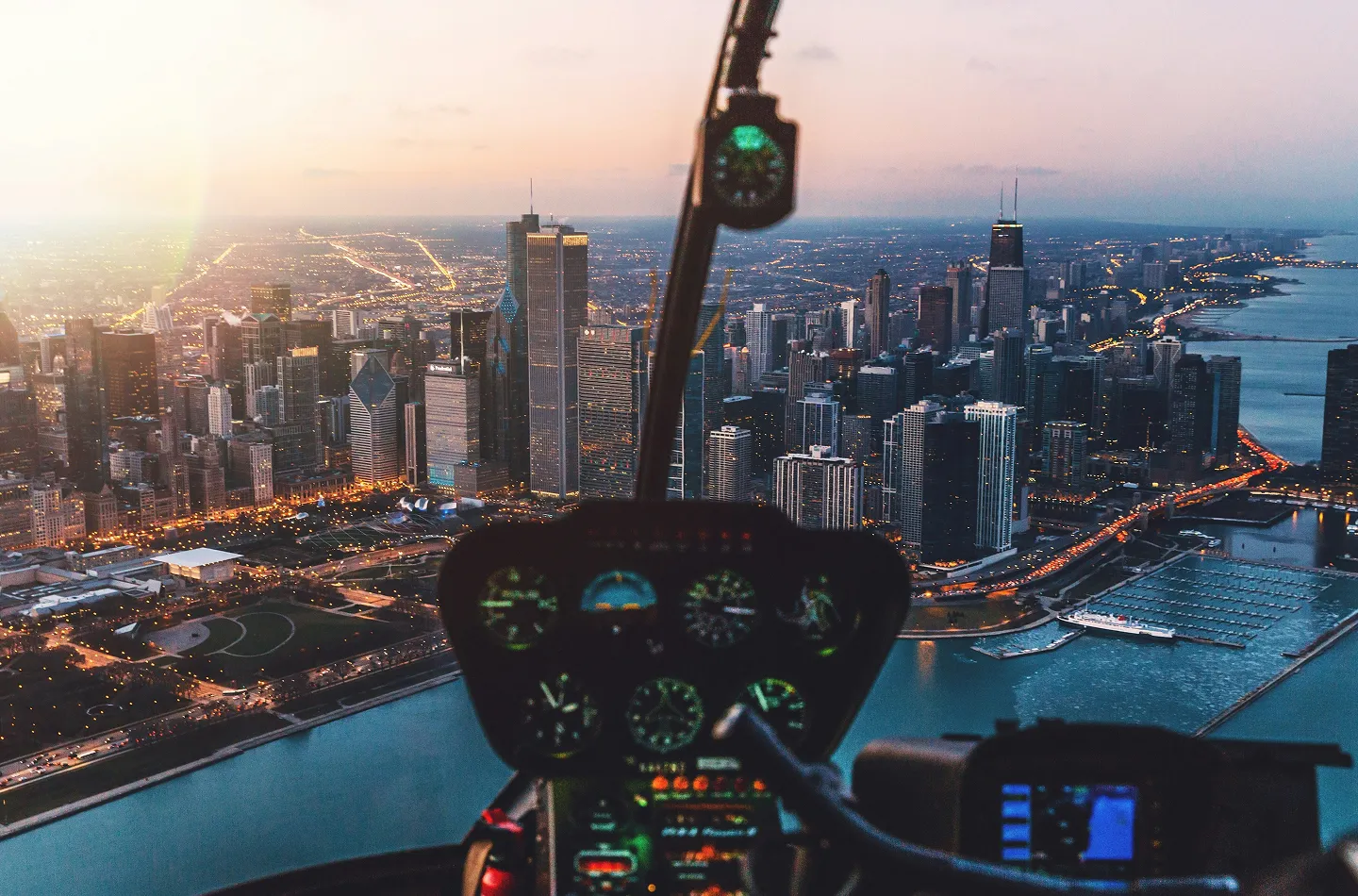 View of Chicago skyline and Lake Michigan at dusk from inside a helicopter cockpit.