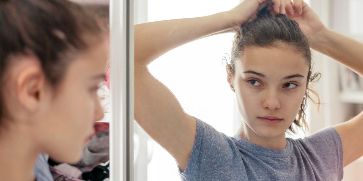 teen girl looking in mirror fixing hair