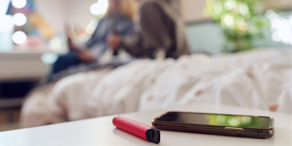 vape beside iphone on teenager's desk