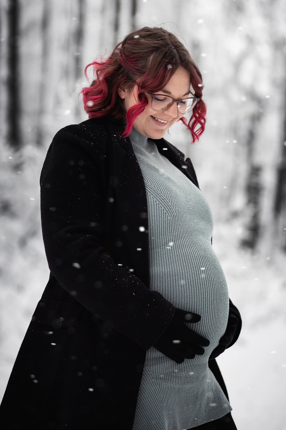 Lächelnde Frau, die sich den Babybauch hält.