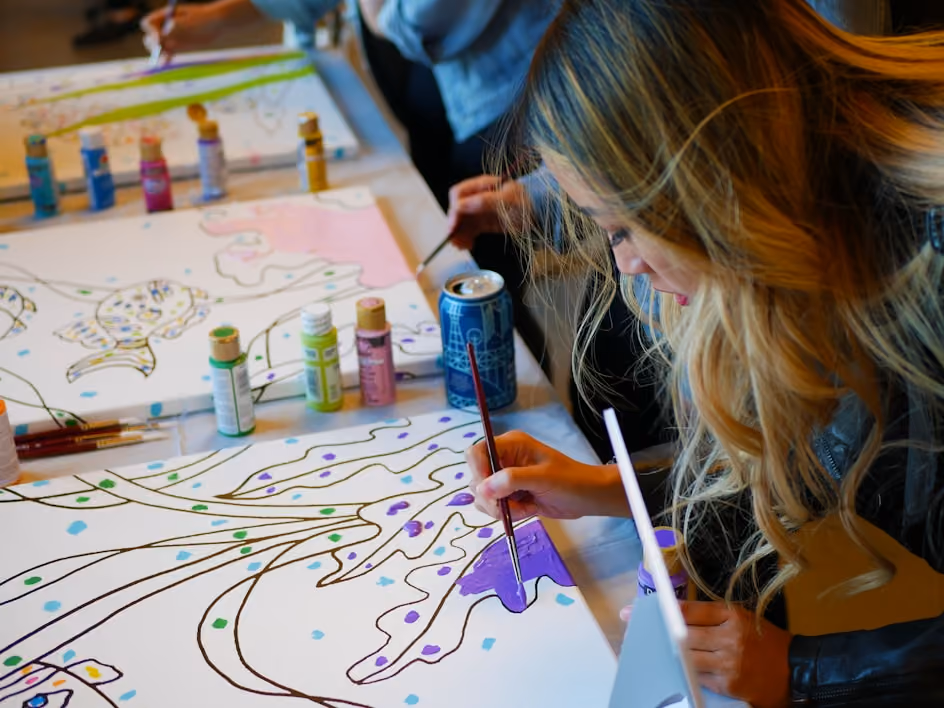 Student painting purple details on a large canvas artwork