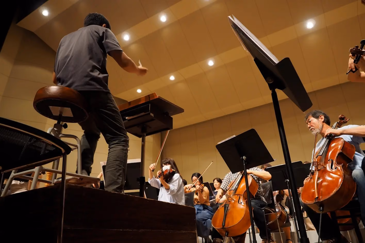 Conductor leading student orchestra rehearsal with string instruments