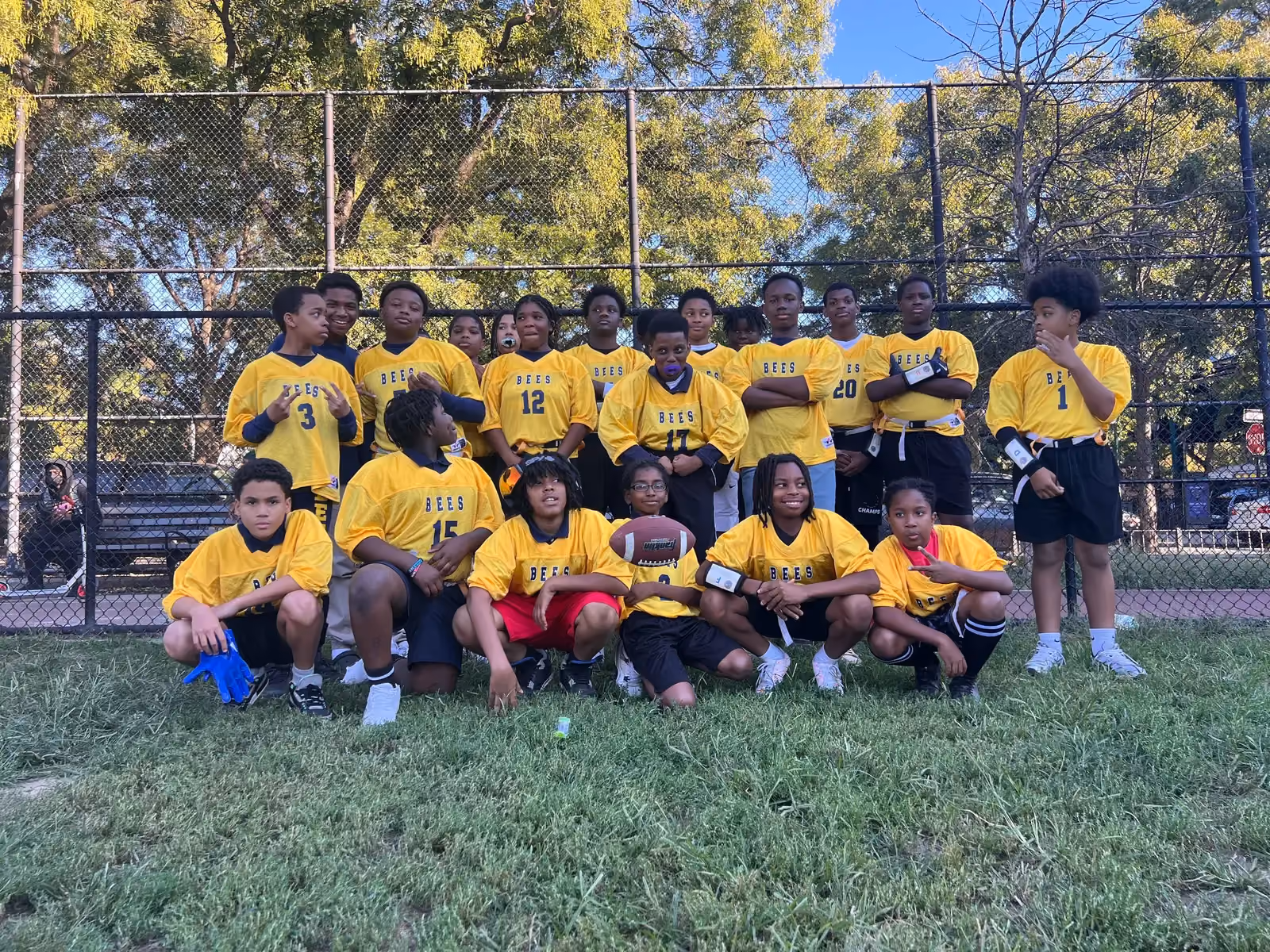 Bees youth flag football team posing together on grass field