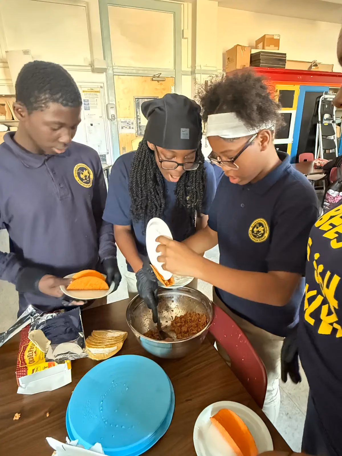 Students in school uniforms assembling tacos during a cooking activity