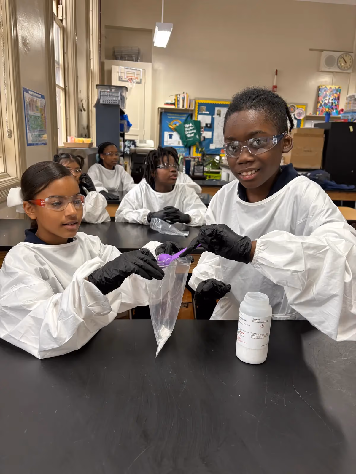 Students in lab coats and goggles conducting a science experiment together
