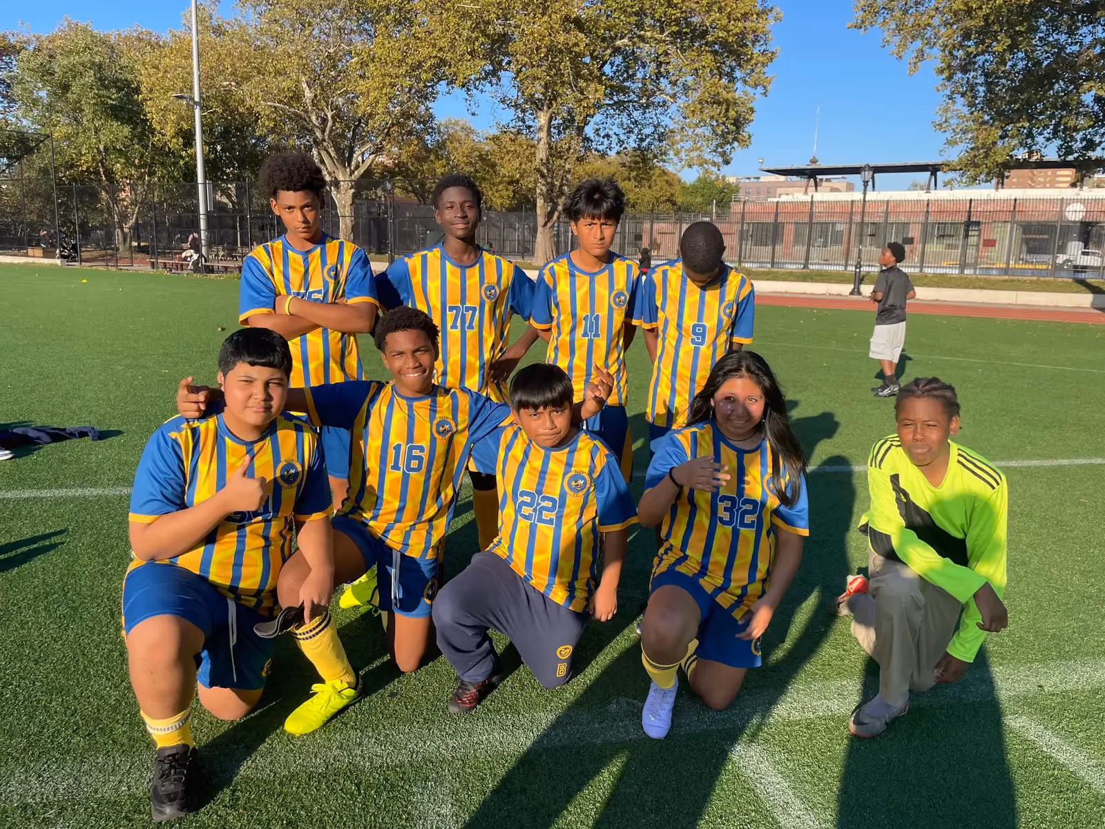 Middle school soccer team posing together on outdoor turf field