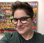 Mx. A Anderson smiling in front of colorful word art