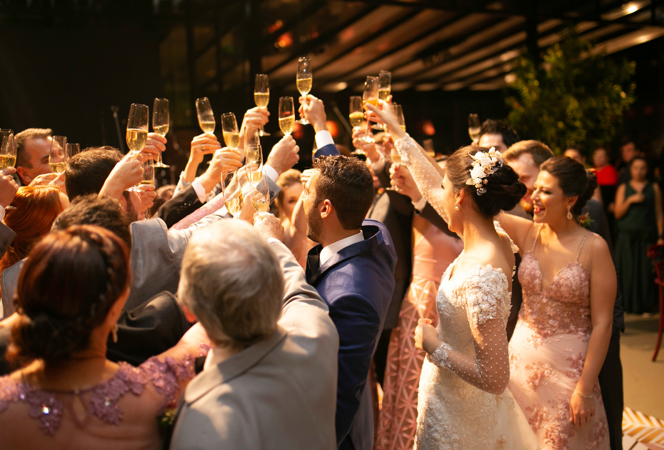 Candid wedding photos of the bride and groom and guests raising glasses of champagne in the air.