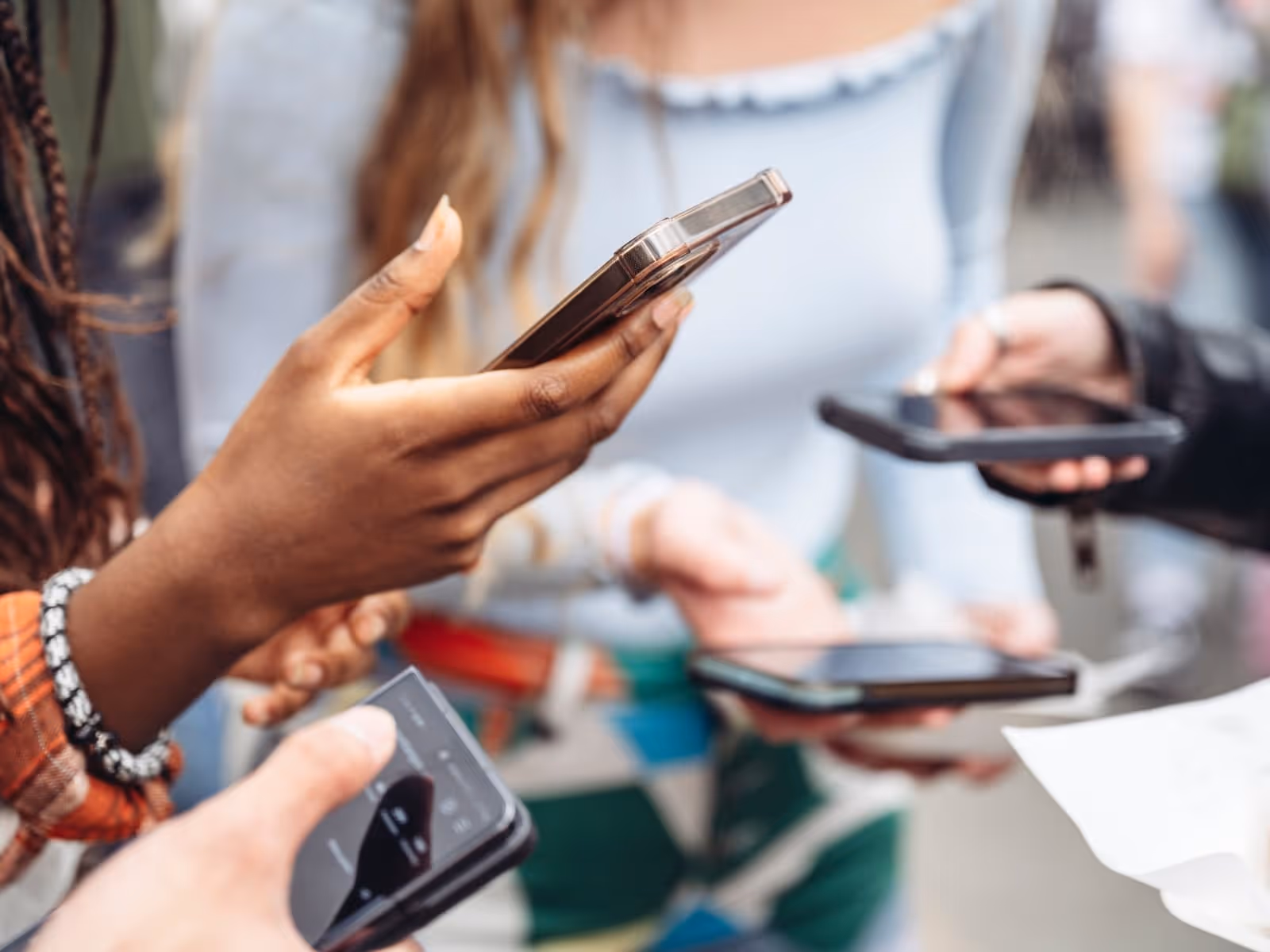 cropped images of 3 young women holding their phones, focus on the hands and phones