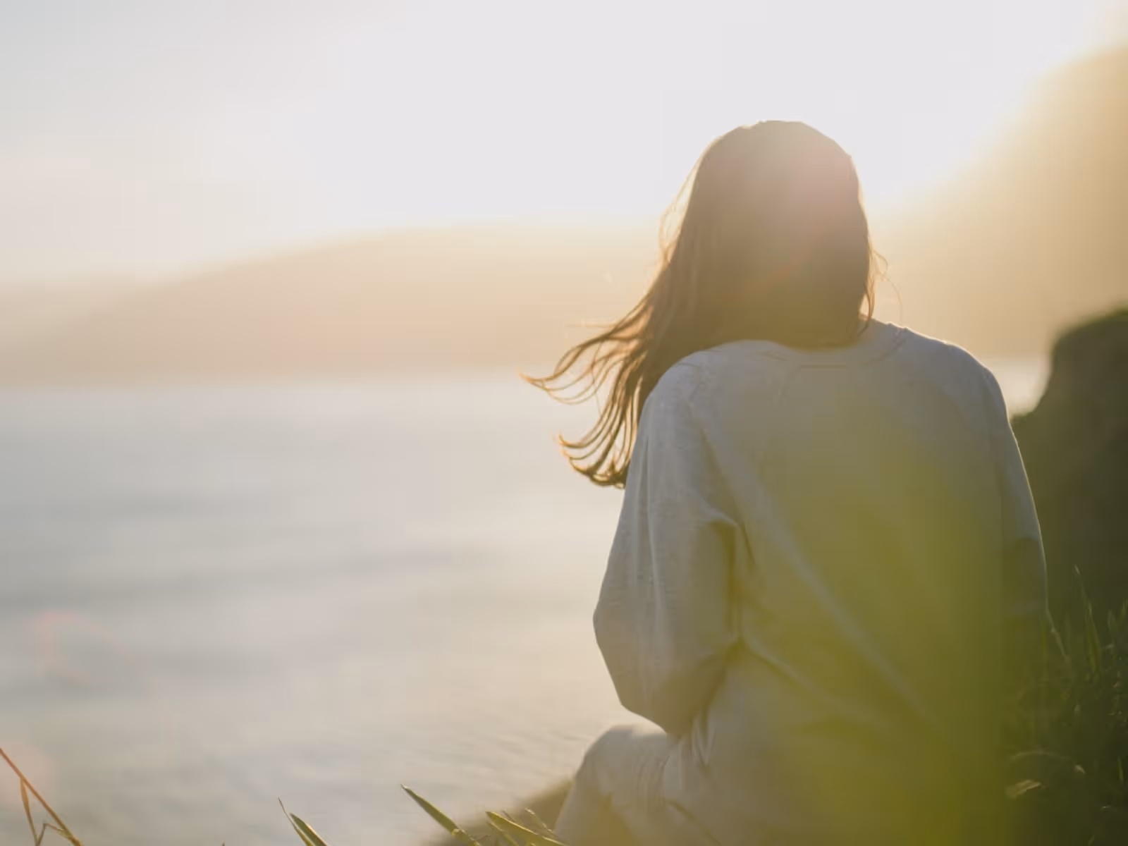 Women sitting on a field looking out to the ocean