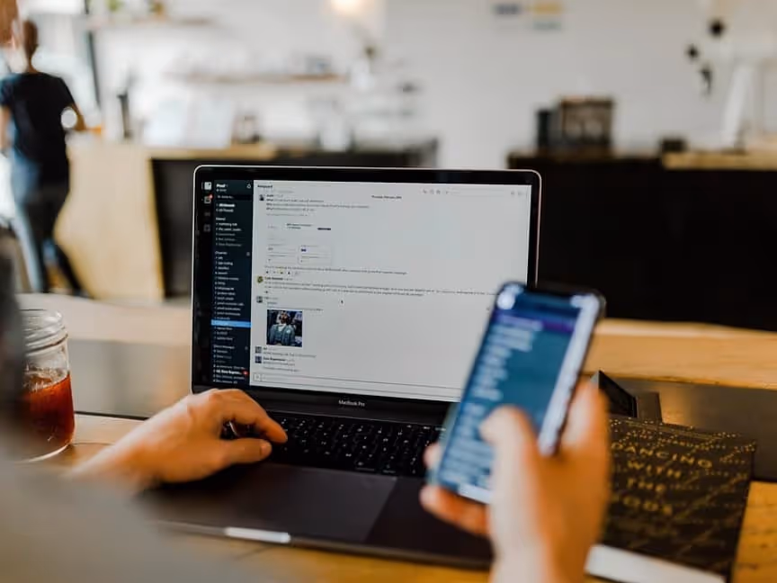 person working on laptop and looking at phone