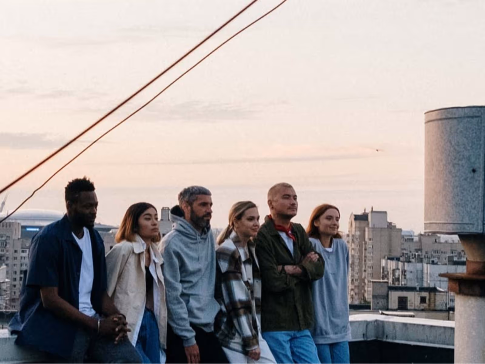 group of friends in line, leaning on a rooftop looking to the distance