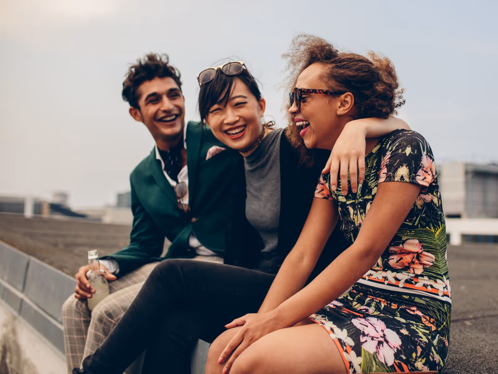 3 friends sitting on a wall and laughing