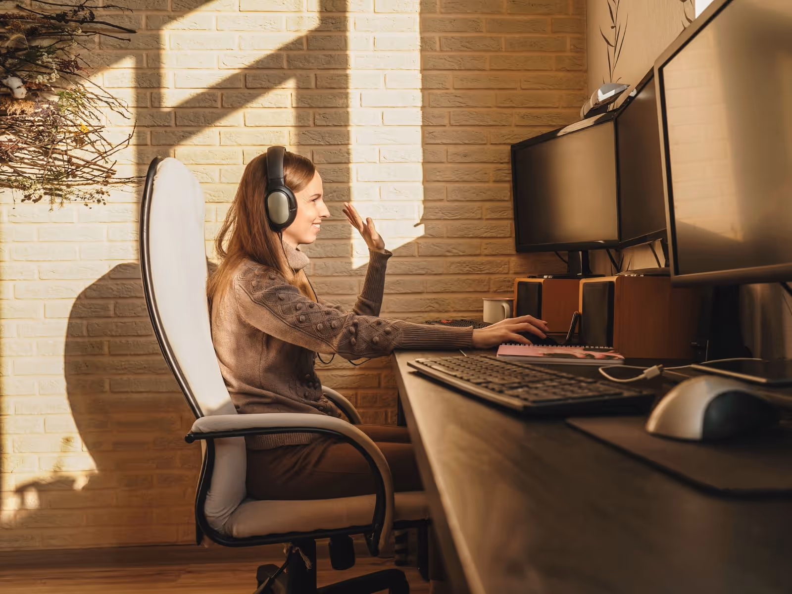 Young women working on a shared office space, greeting people on an online meeting.