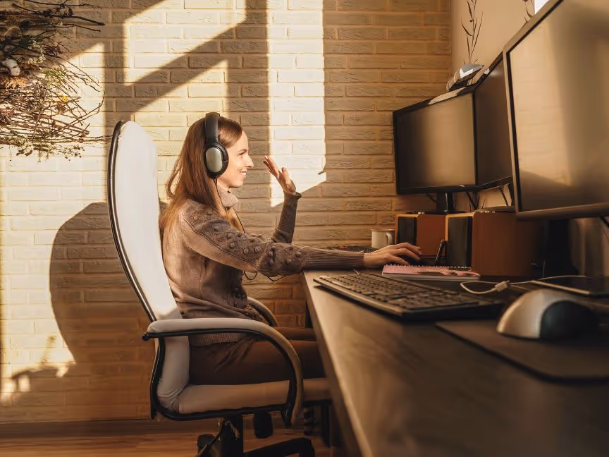 Young women working on a shared office space, greeting people on an online meeting.
