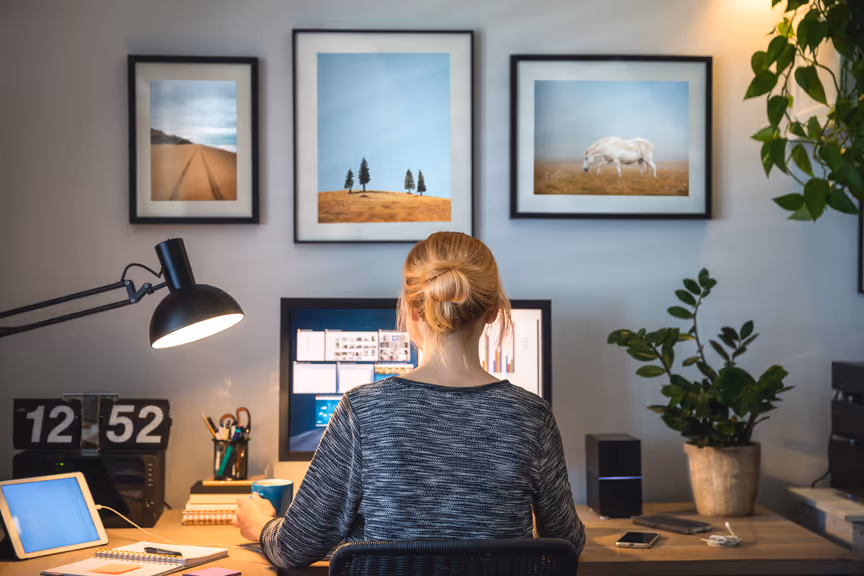 Woman seen from behind, sitting at a desk and working on her computer in a home office setting