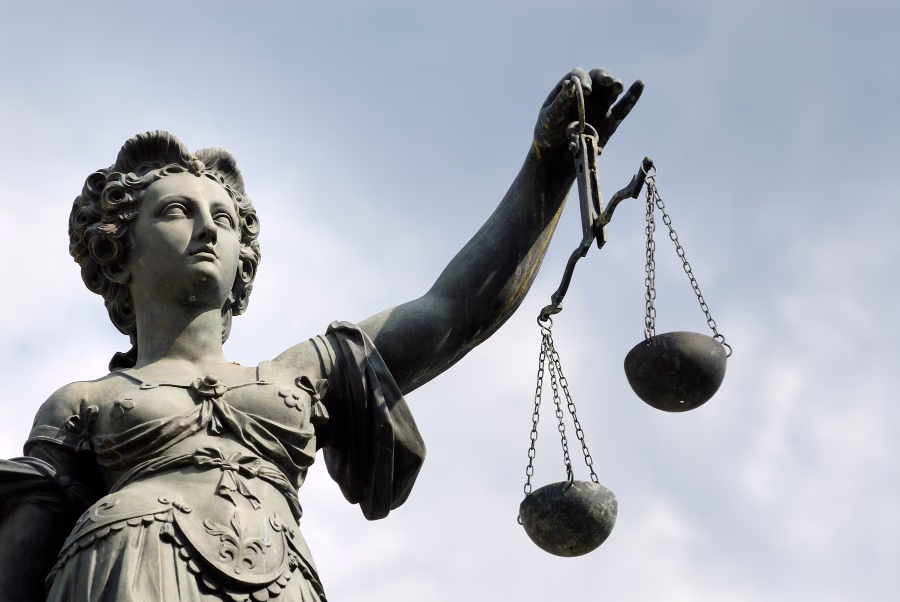 Close-up of a statue holding a balanced scale of justice, symbolizing fairness and impartiality
