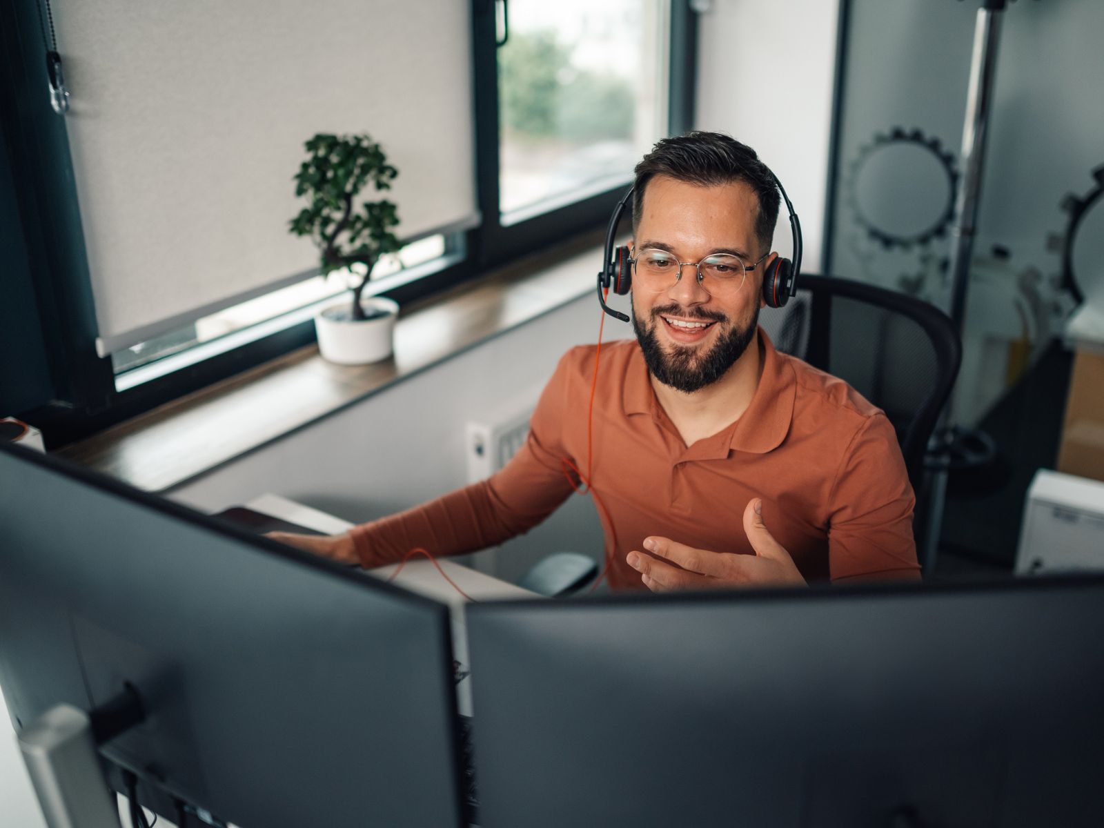 Man working from home wearing headset in front of two screens
