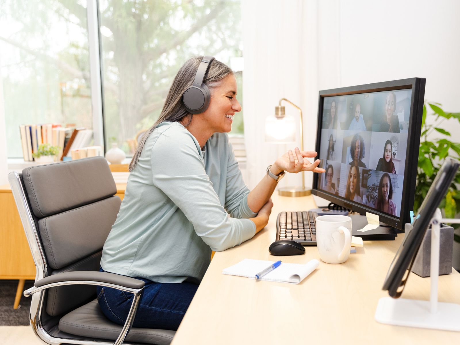 Woman sitting at her home office with headset talking in an online meeting