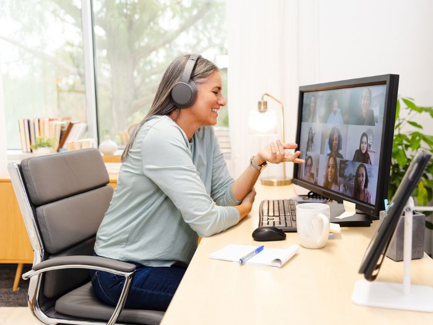 Woman sitting at her home office with headset talking in an online meeting