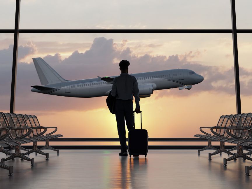 Man standing looking at a plane taking off in the airport through the windows