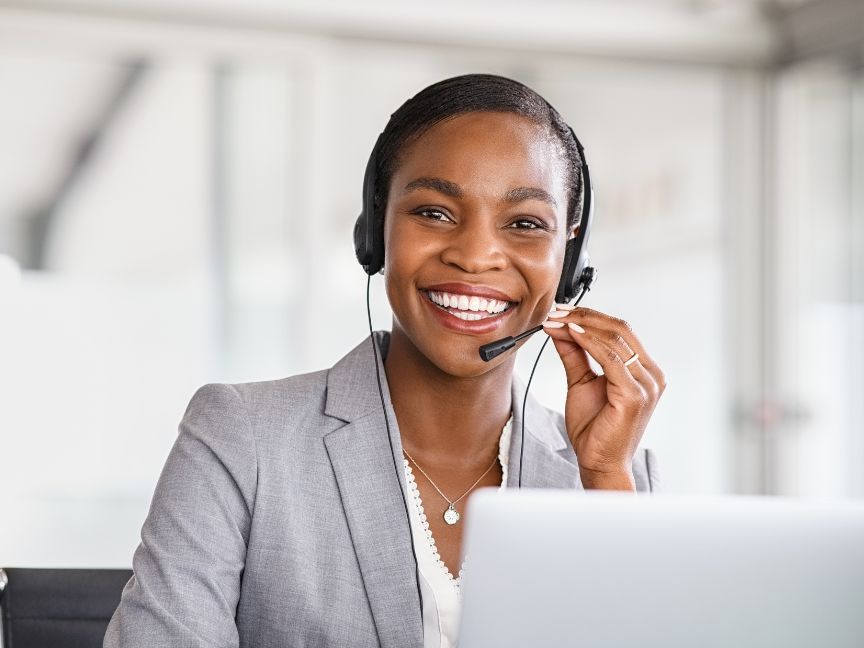 Woman sitting in front of computer smiling with headset on