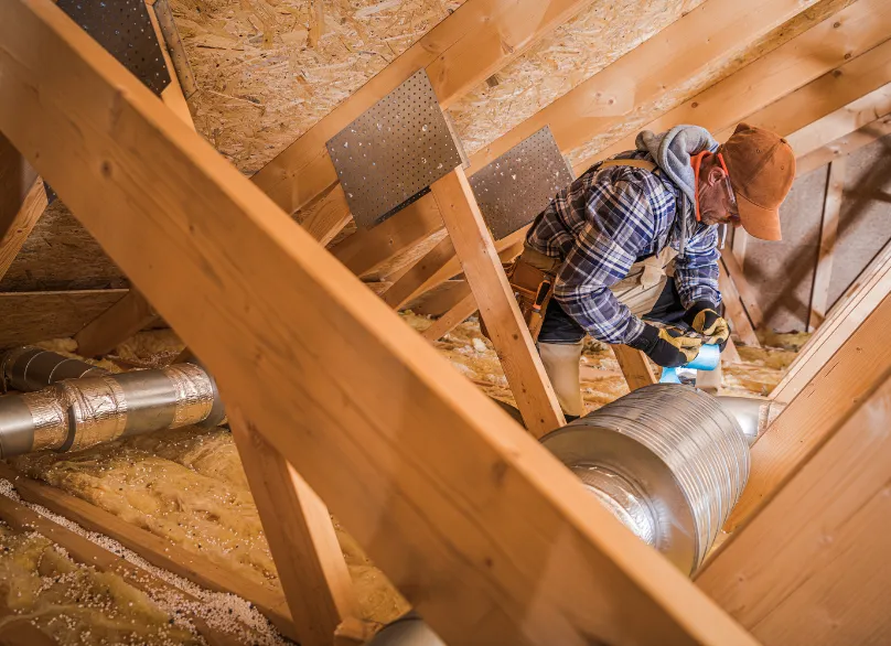 Technicien intervenant sur une installation gainable dans les combles