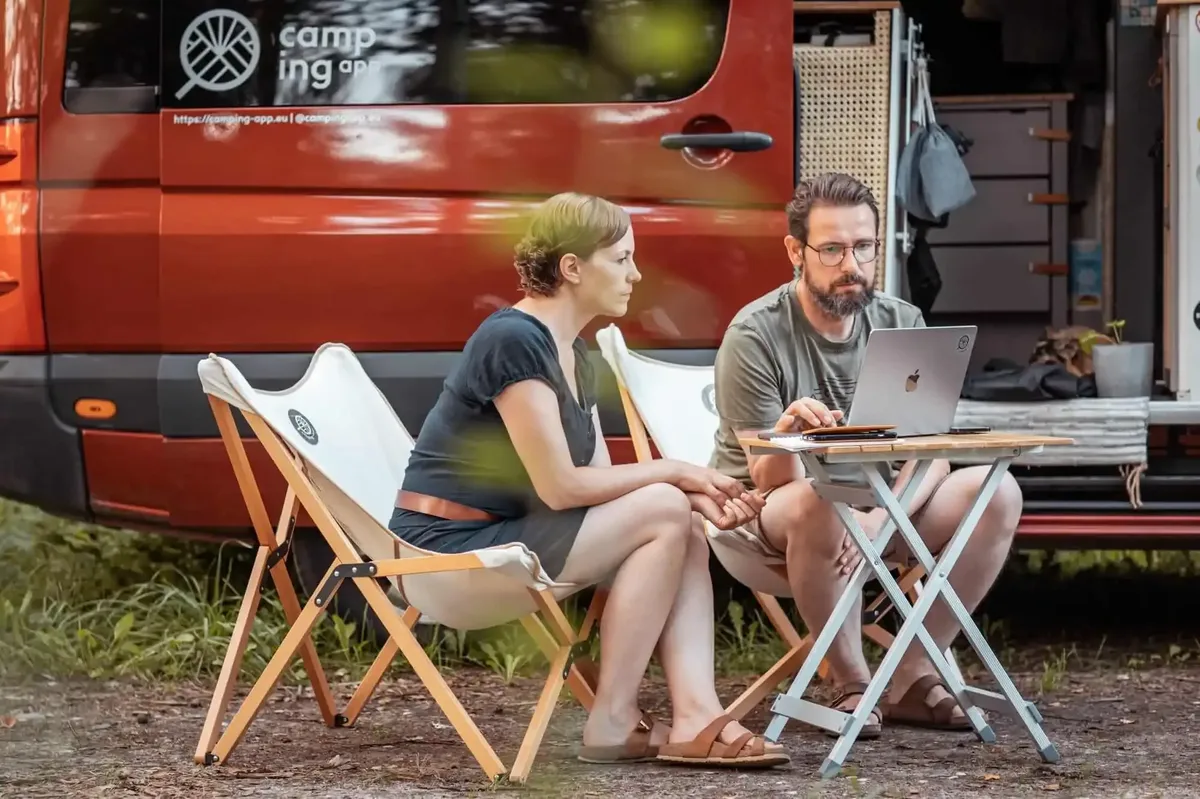 Jenny and Lukas working on their laptop in front of their van
