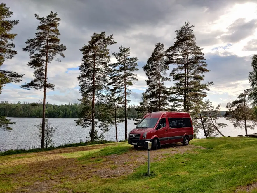Der rote Camping-App-Van steht am See in Schweden