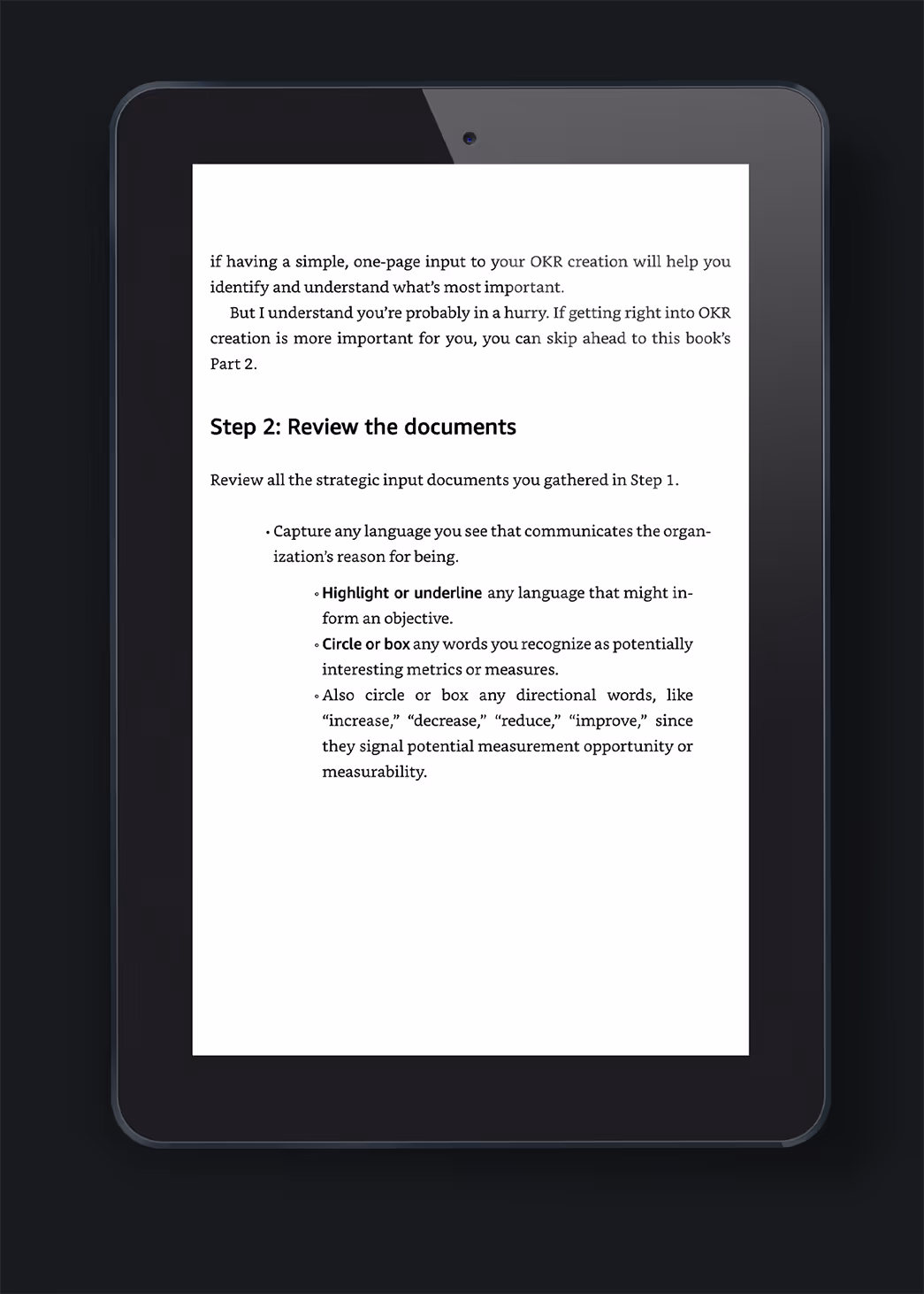 A tablet displaying a text document titled 'Step 2: Review the documents,' outlining strategies for identifying organizational goals and objectives, with bullet points emphasizing language and measurement interests.