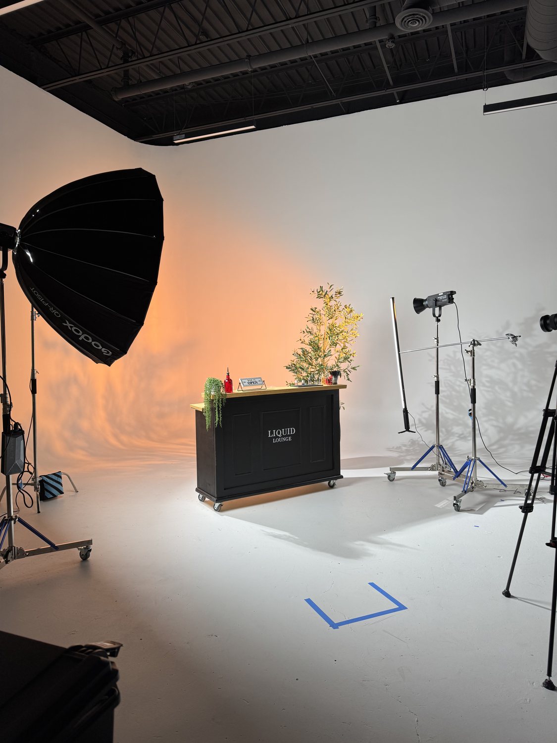 A styled bar cart on the cyclorama wall lit with a warm orange wash and two studio lights