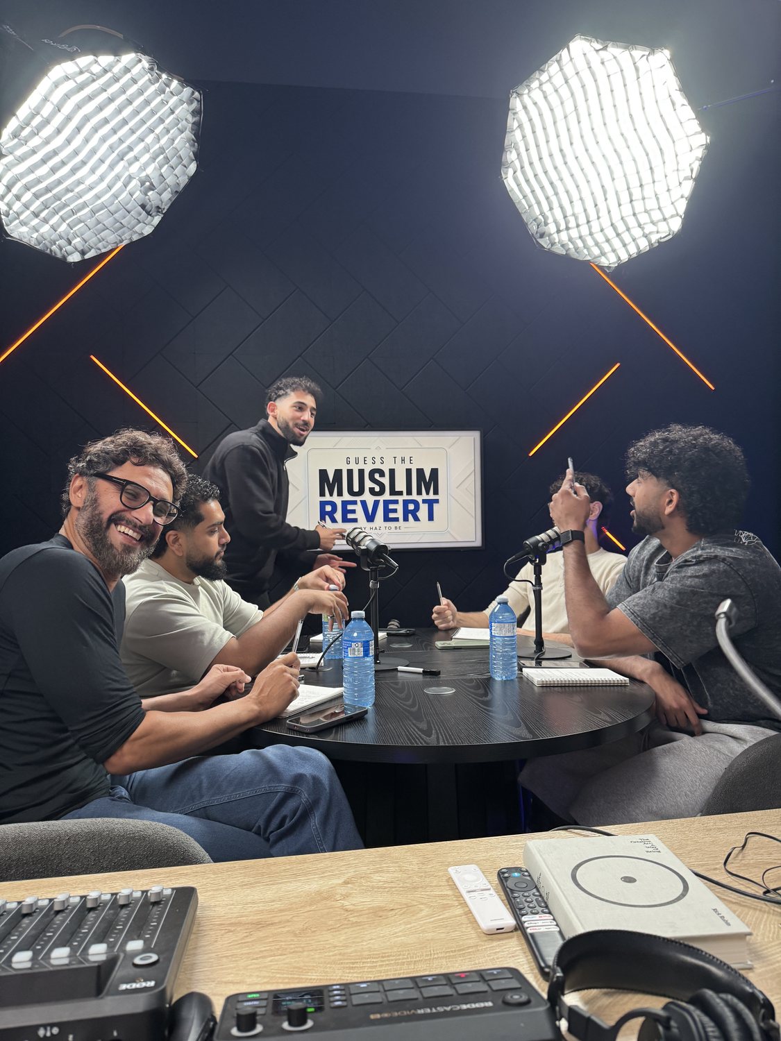 A podcast panel laughing between takes in the Podcast Studio, with the audio control desk in the foreground