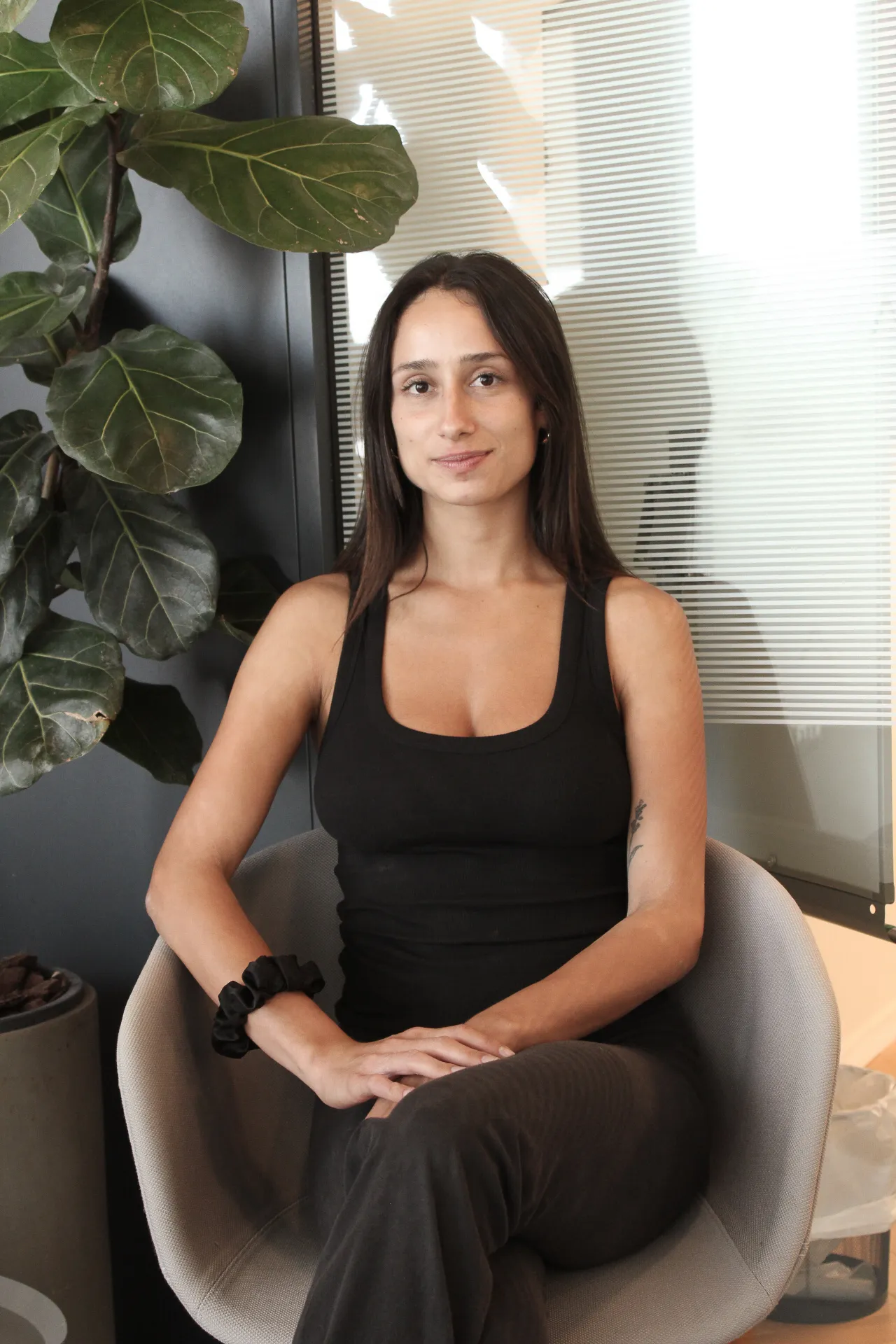 A woman sitting in a chair next to a plant.