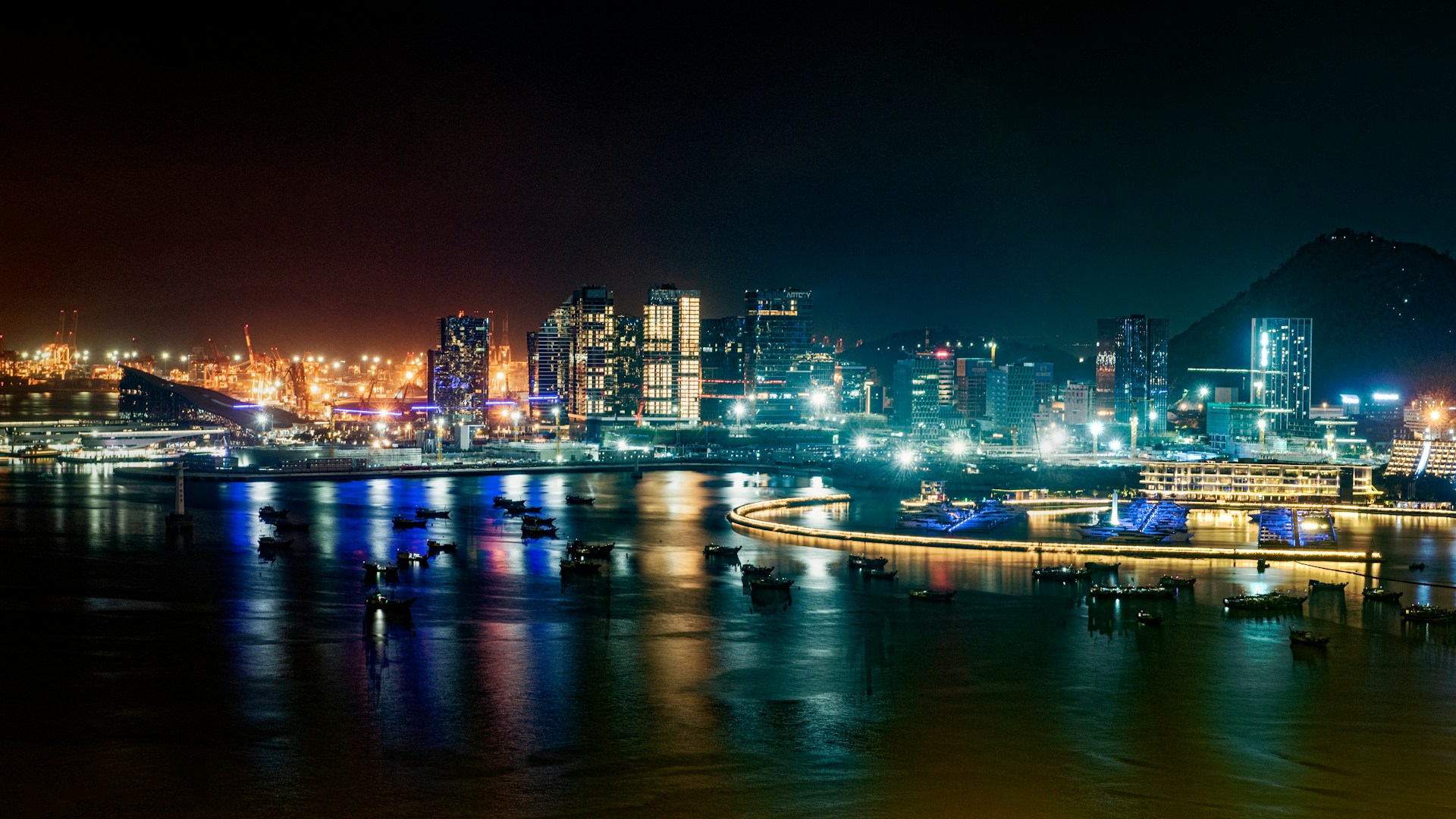 Shenzhen harbor at night with skyline reflections on water