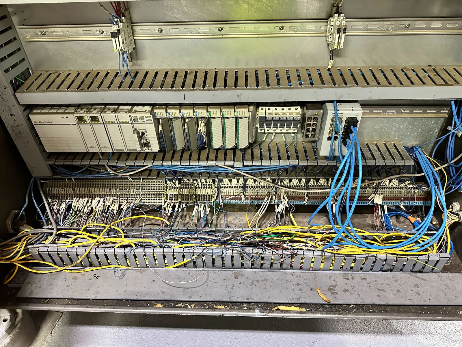 Legacy PLC rack before rebuild, mounted on the original backplane with loose wiring across it.