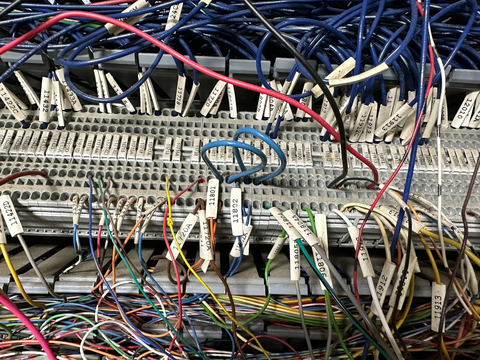 Terminal strips before rebuild, with wire-marked conductors landed across them and loose bundles looping above.