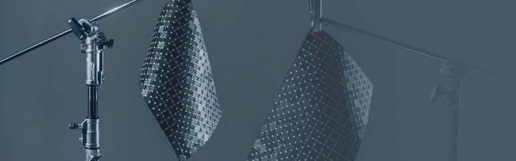 Flexible solar panels with a patterned grid design hanging in a studio setup.