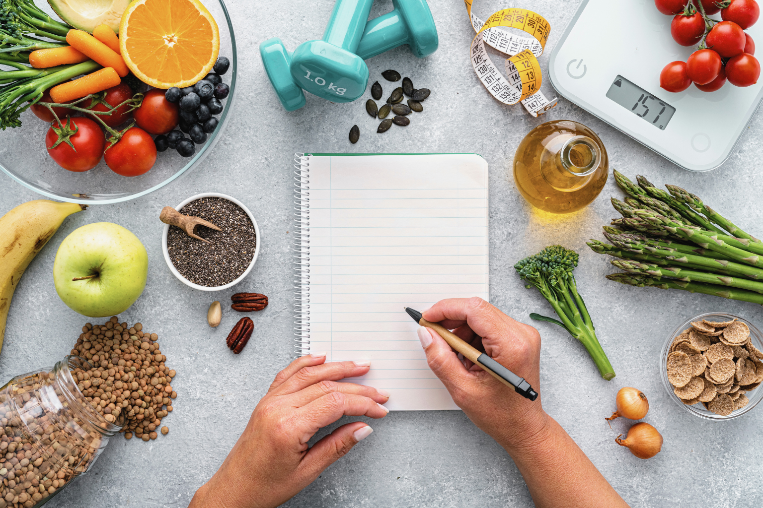Healthy lifestyle planning setup with fruits, vegetables, weights, and a journal, symbolizing wellness coaching and goal achievement.