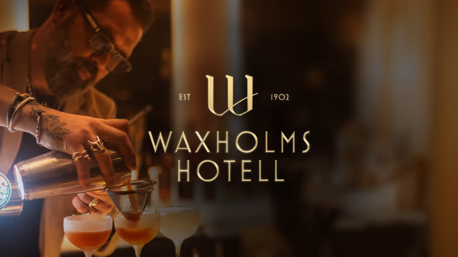 Banner showing a dark textured background with a golden logo for Waxholms Hotell on top, slightly illuminated.
