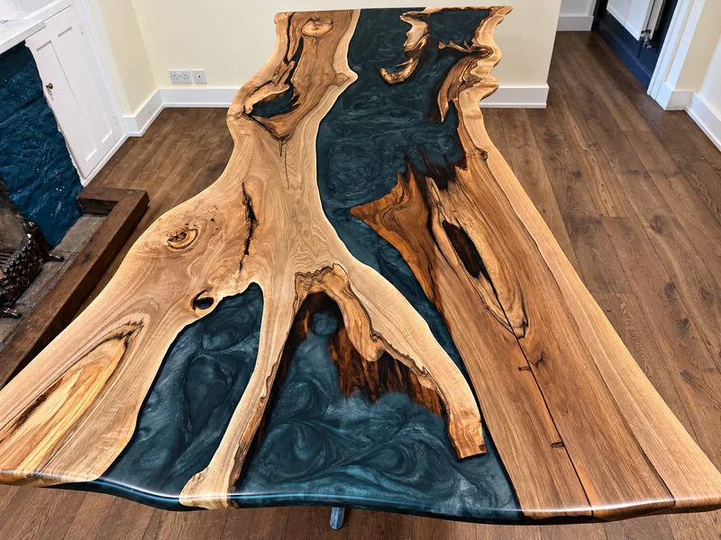 Live-edge walnut table top with a deep blue resin river flowing between the boards