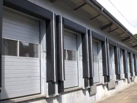 Reihe geschlossener grauer Laderampentore an einem Industriegebäude.