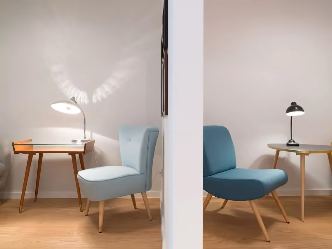 Lounge mit hellblauem und türkisfarbenem Sessel auf Holzbeinen, kleinen Holztischen