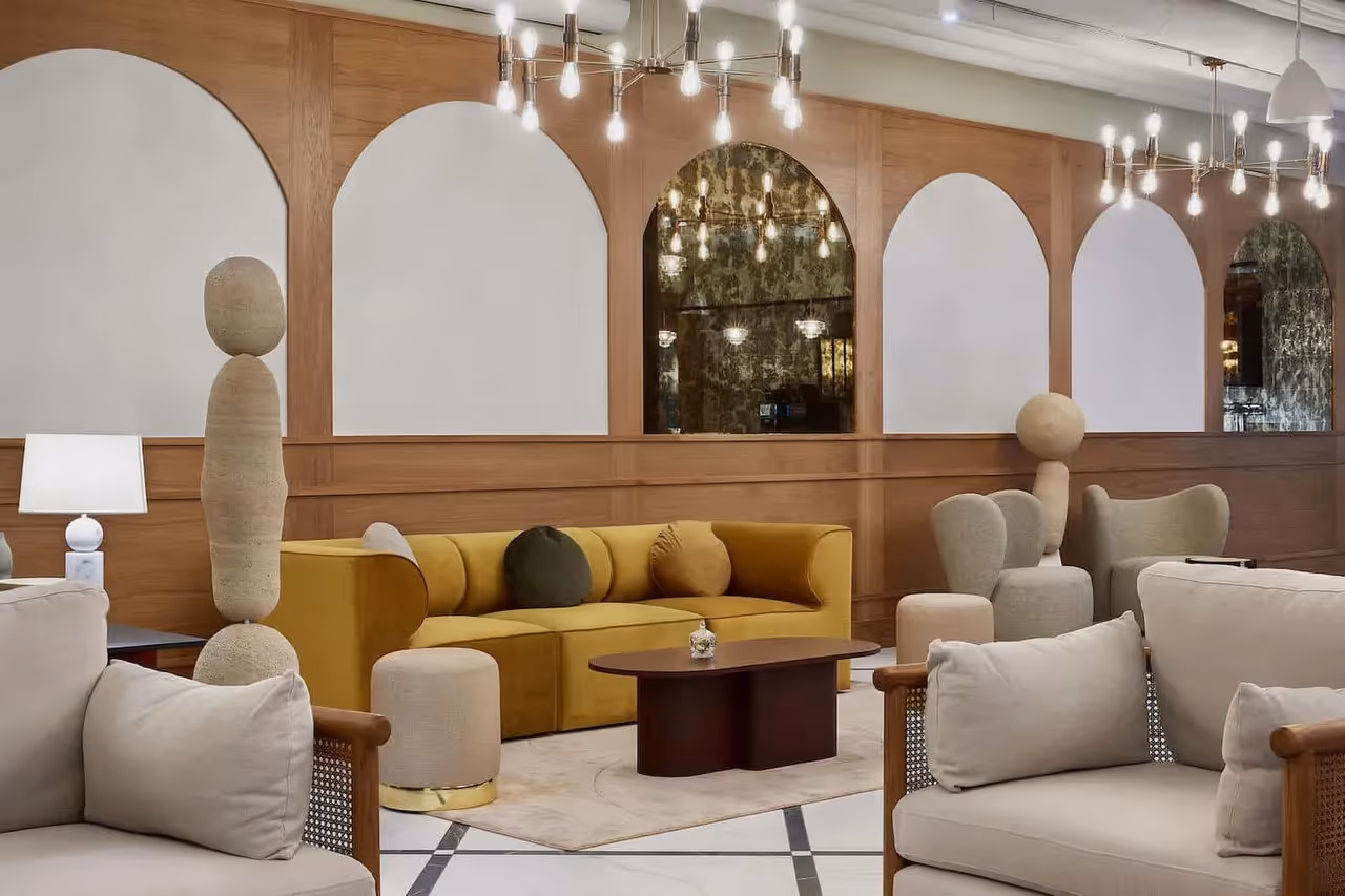 Gemütliche Sitzecke mit gelbem Sofa, runden Sesseln, Holzwandverkleidung und moderner Beleuchtung.
