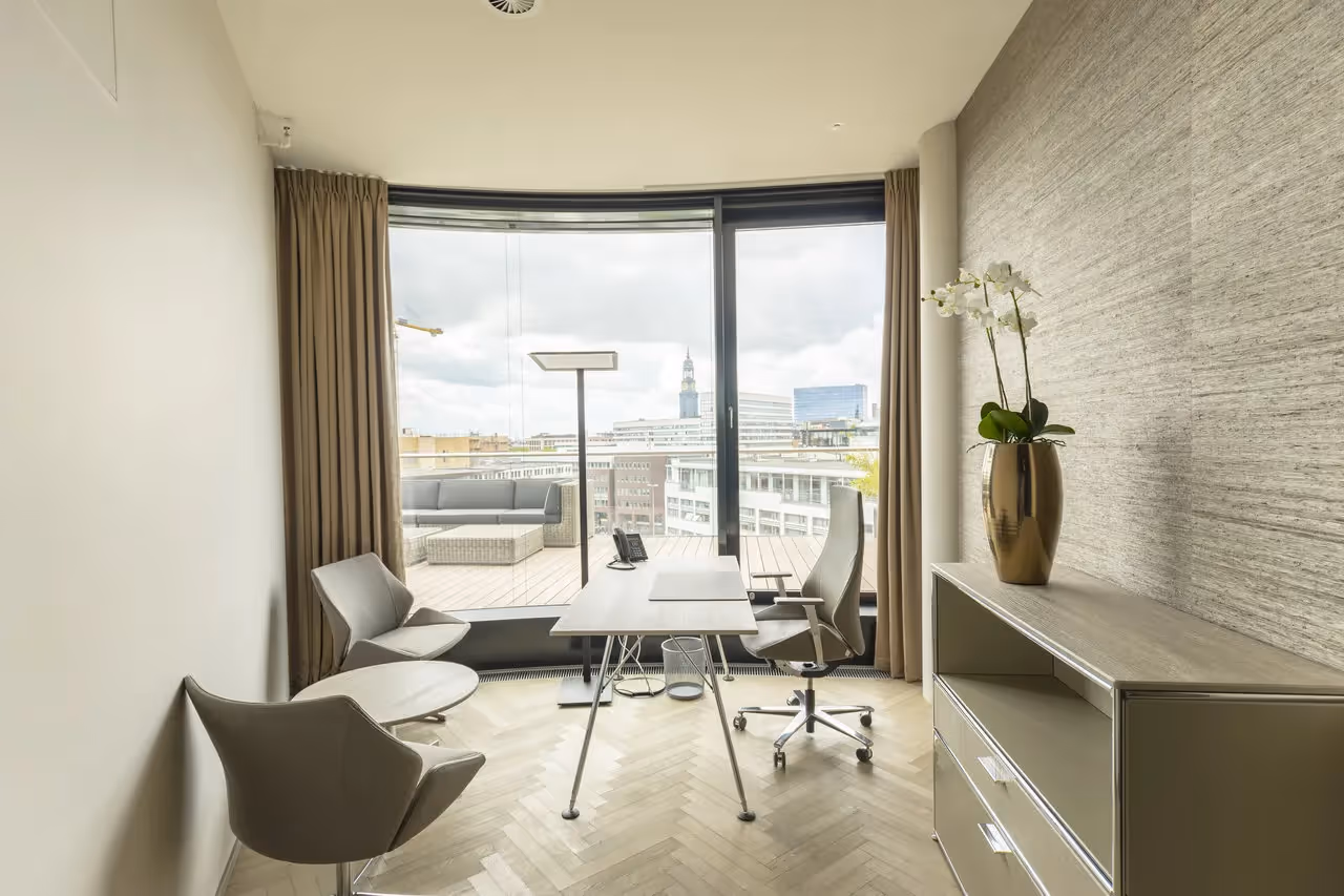 Helles Büro mit Schreibtisch, zwei Stühlen, großer Fensterfront, Vorhängen und Pflanze auf Kommode, Blick auf Terrasse.