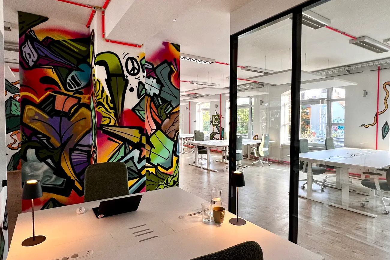Coworking area with desks, graffiti wall and glass-walled meeting room at werkhain