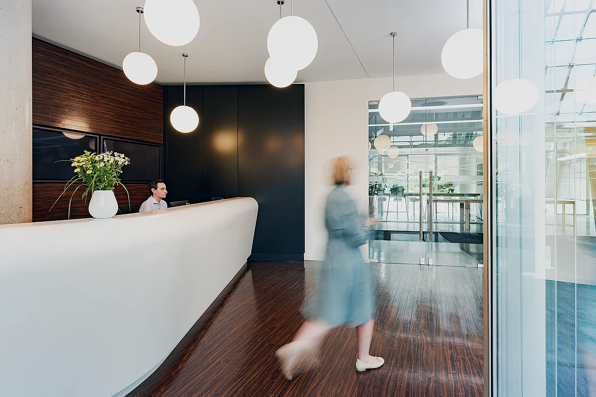 Reception desk with globe pendant lights and glass facade at ecos work spaces in the Berliner Bogen, Hamburg