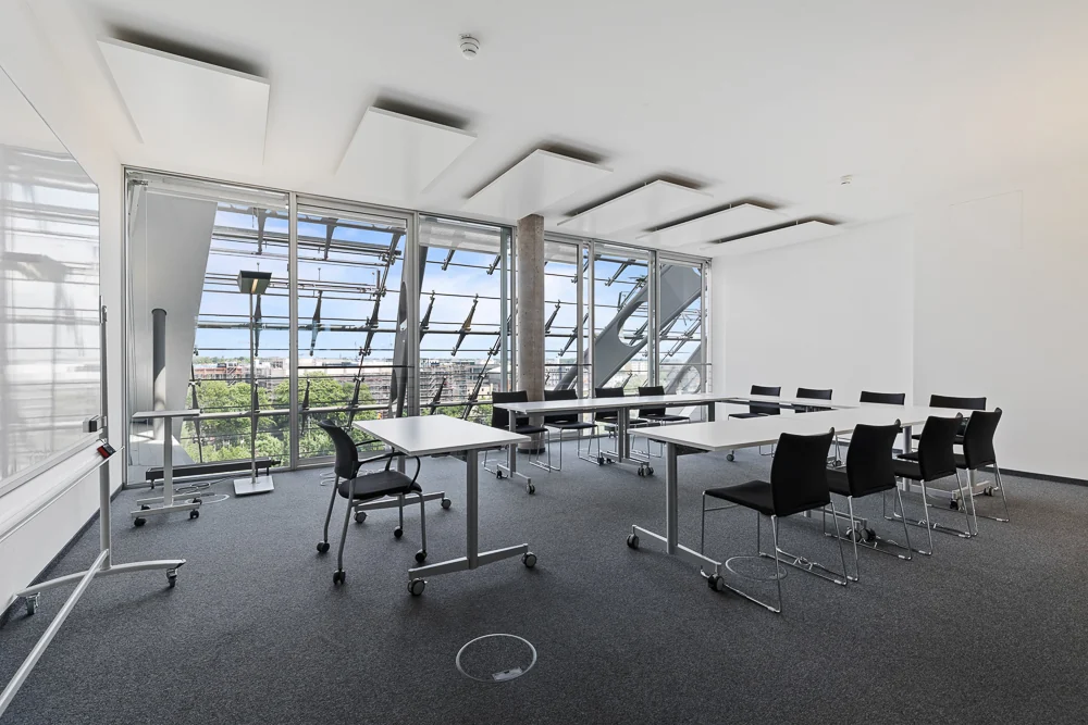 Seminar room with mobile tables and a view of the glass facade's steel structure in the Berliner Bogen, Hamburg
